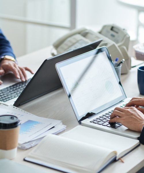 Cropped image of business people working on laptops in office